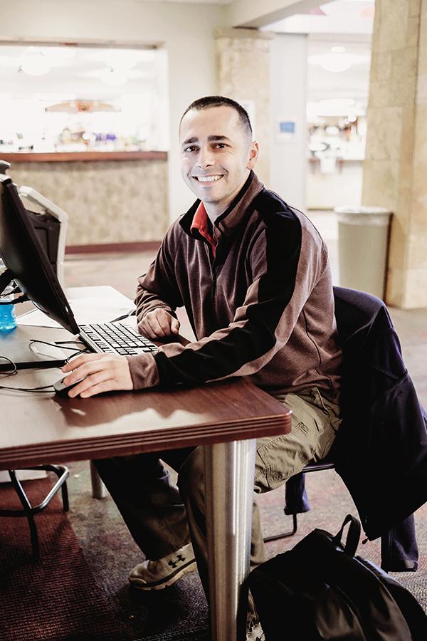 A student at a computer smiles for the camera